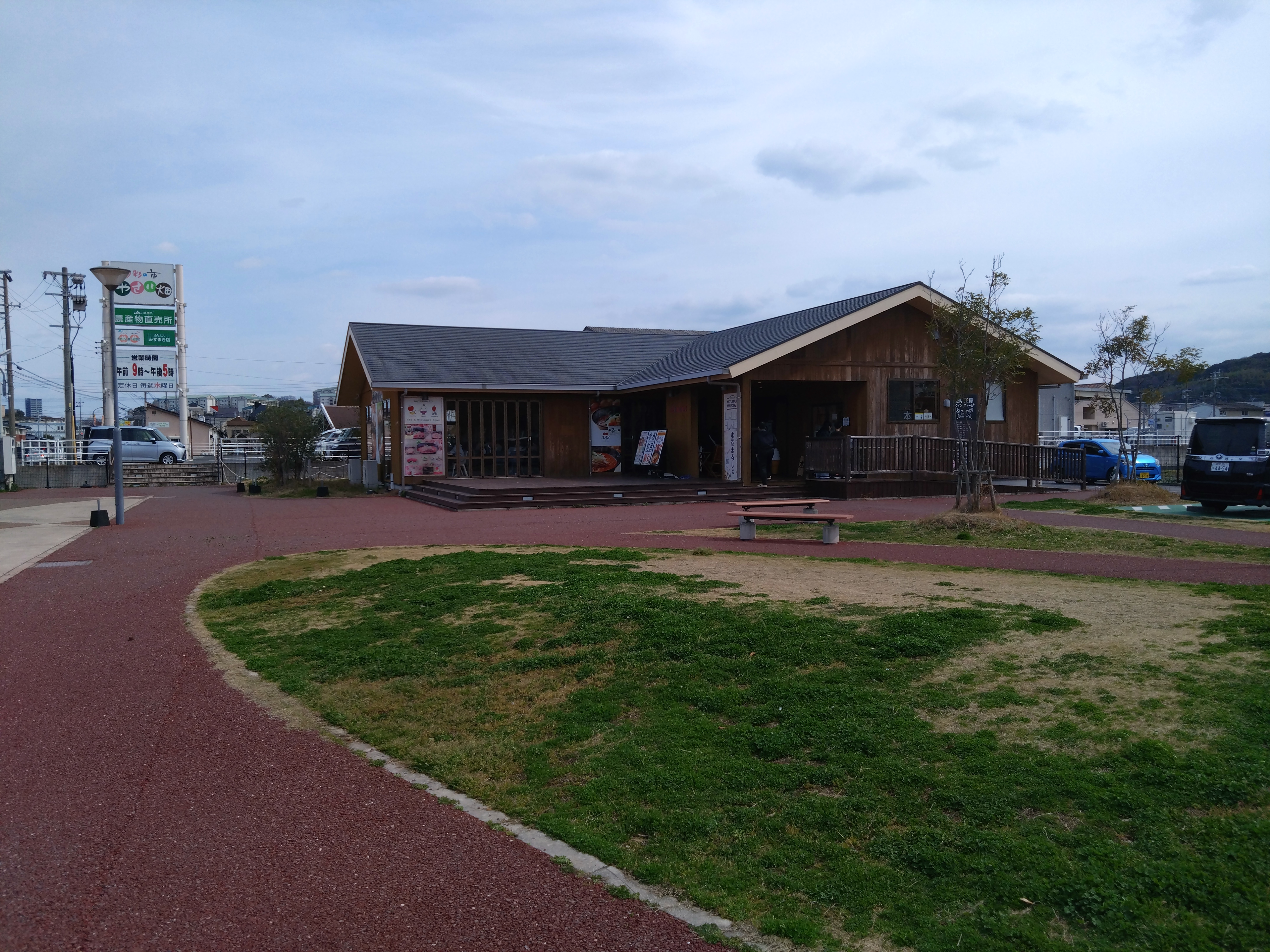 公園にある木造の建物と遊歩道、周囲には植えられた木々と芝生があります。